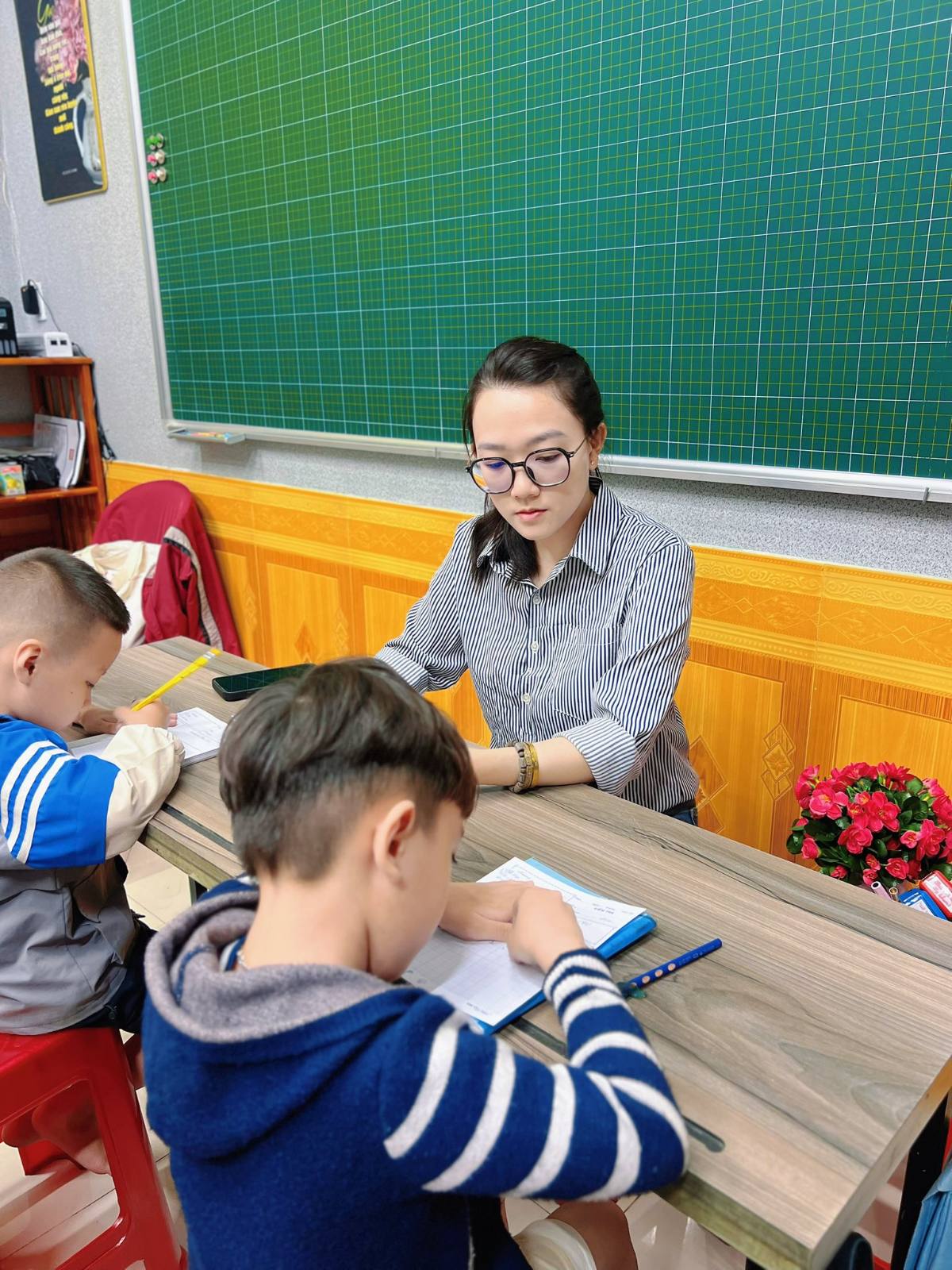Cô giáo theo dõi hai bé làm bài kiểm tra đầu vào